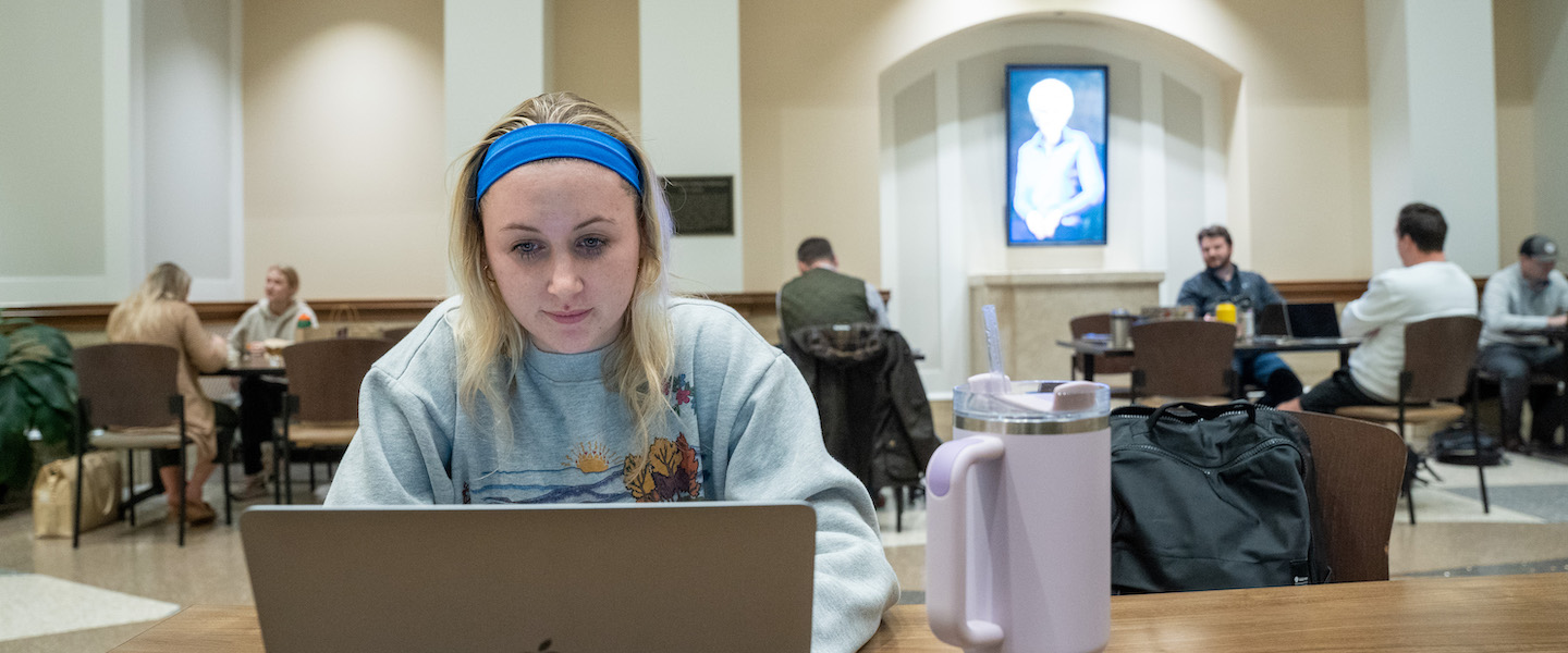 Graduate student studying on laptop in Barbara Massey Rogers Center lobby