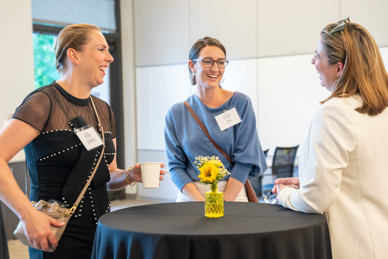 Three female SCOPE Reunion attendees talking and laughing around standing table