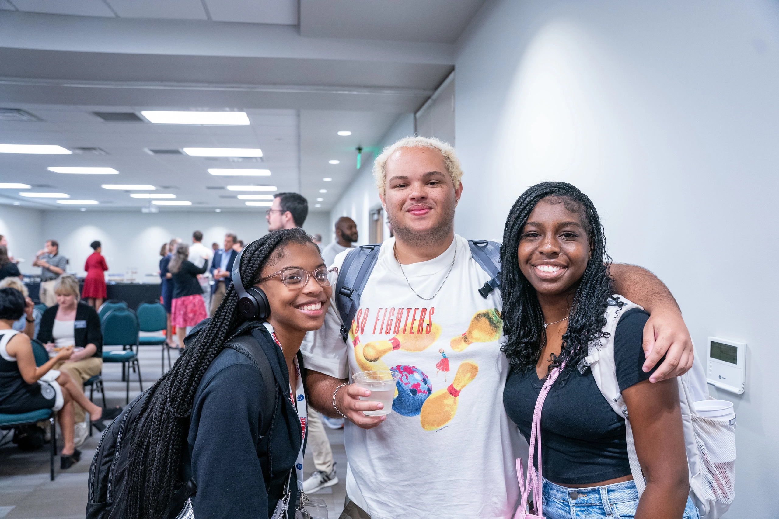 Three Belmont students smiling at the camera at a HUB office event