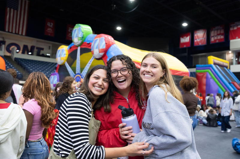 Group of three students posing amid fall festival