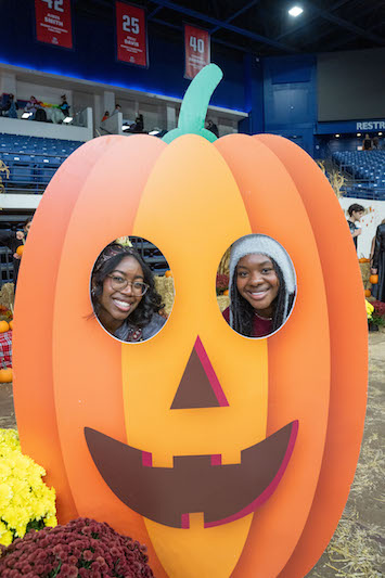 Two students pose in a pumpkin photo booth