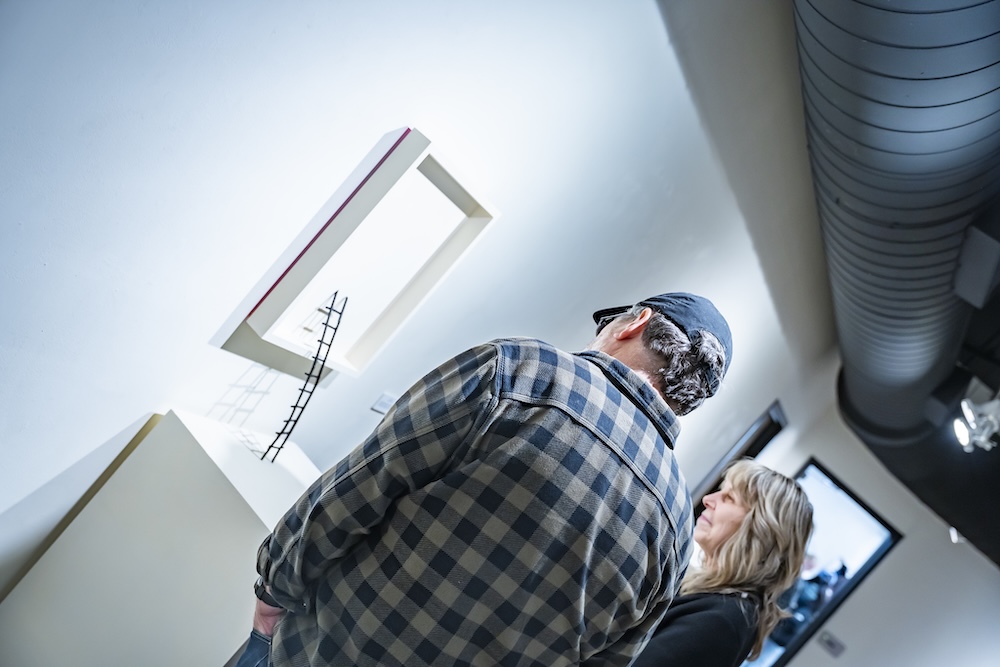 two people looking at a ladder art piece in the gallery