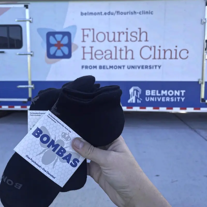 Bombas socks being held up in front of the Flourish mobile clinic.
