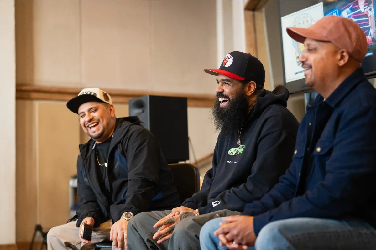 Stalley sits with two friends, laughing during an indoor panel discussion