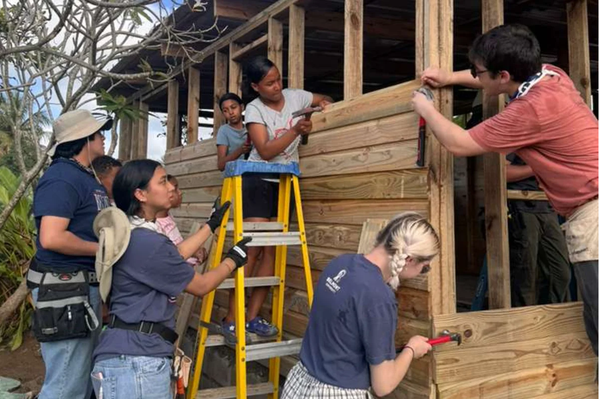 A group of students holding a banner at a work site