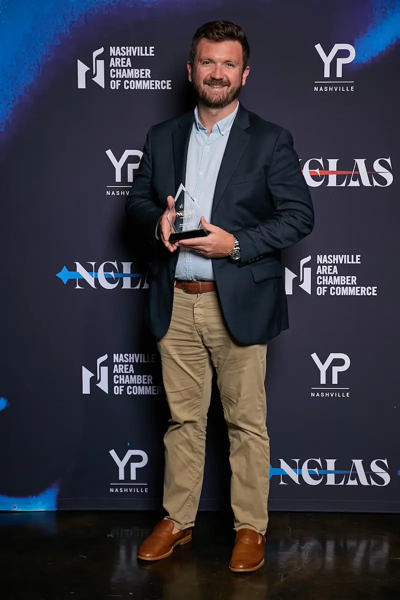 Steven Henry holding award in front of step and repeat