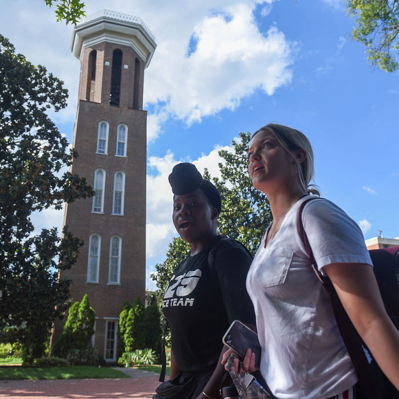 Two students walking in front of the Bell Tower