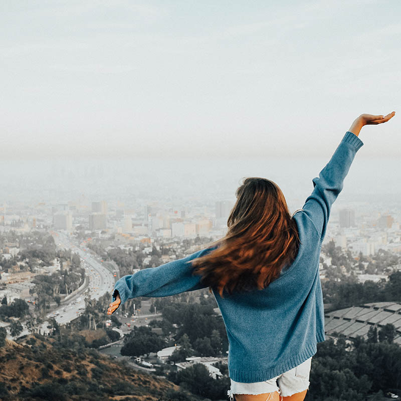 Belmont USA student poses with her arms out while facing the city of Hollywood on a hill