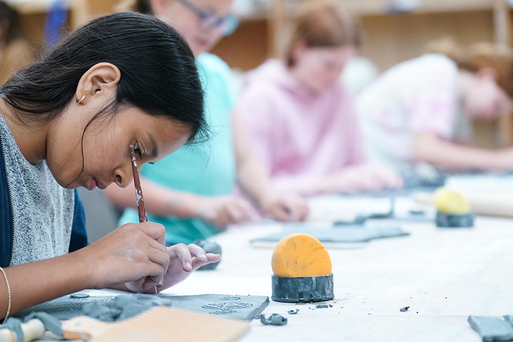 Student carving pottery in classroom