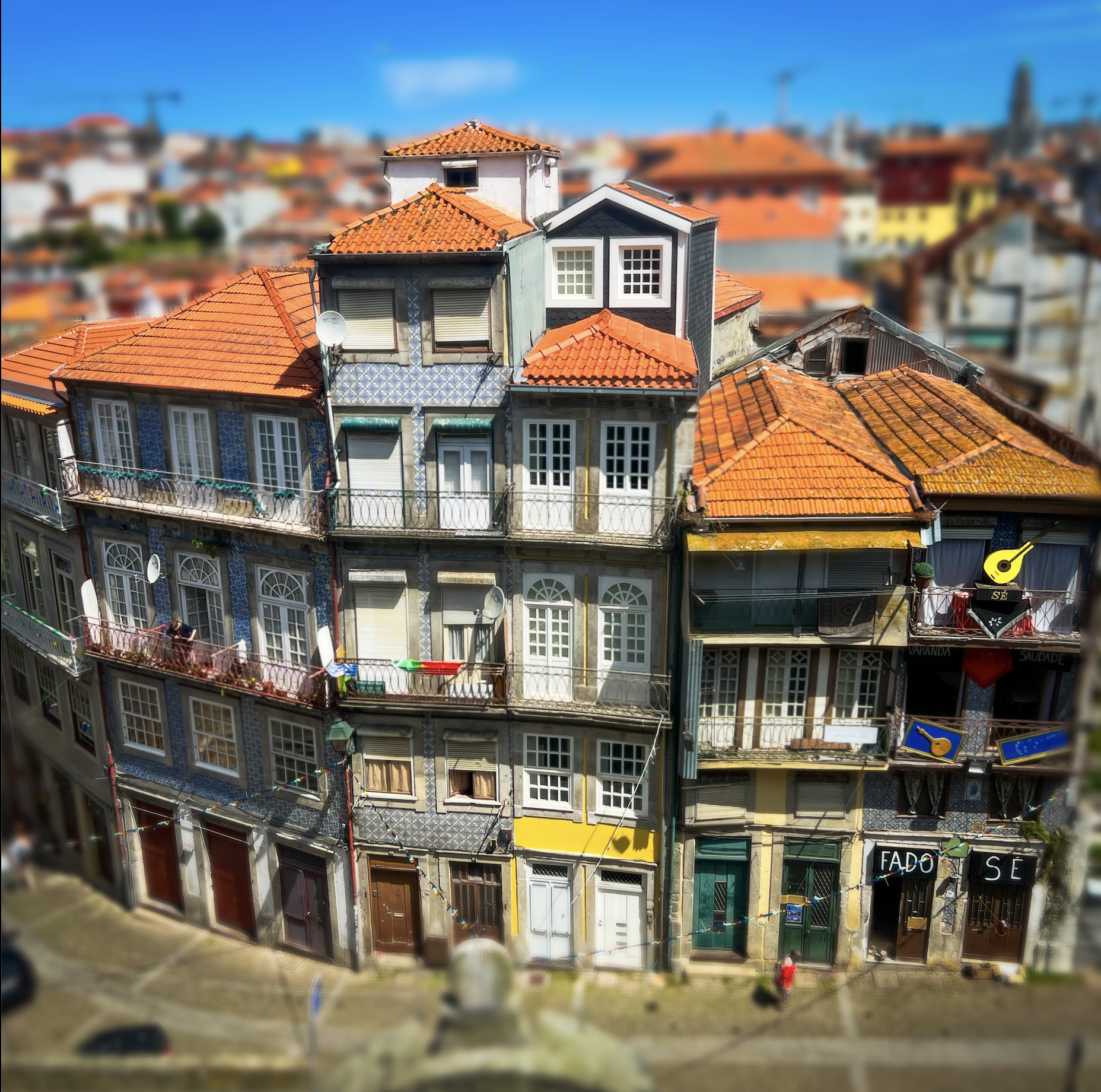 Colorful multi-story European buildings with terracotta rooftops, tiled facades, and wrought-iron balconies overlooking a narrow street.