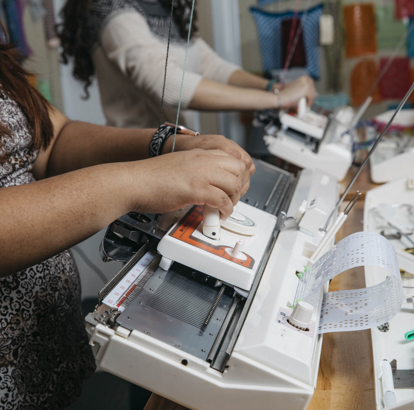 a person joyfully works the knitting machine