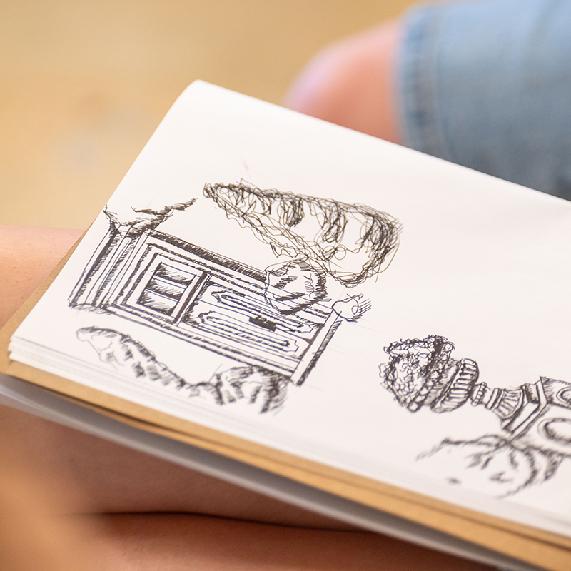 Close up of a sketchbook that shows textural drawings of architectural details and plants 