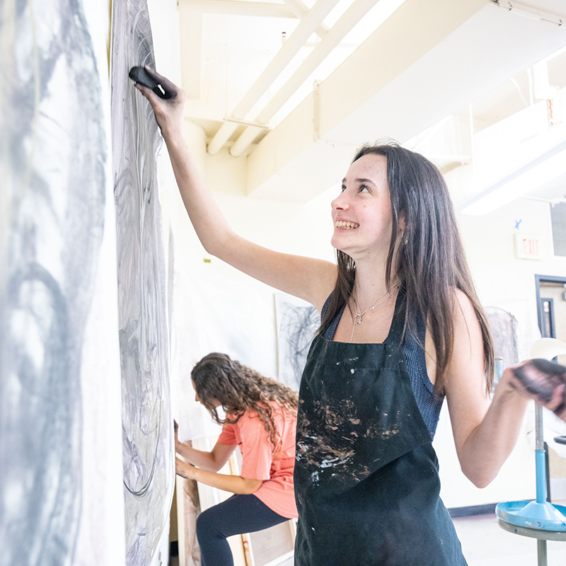 image of student drawing on a large piece of paper taped to the wall