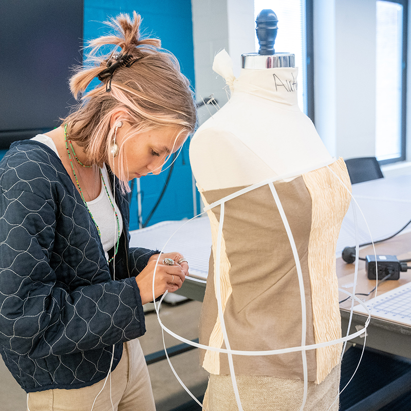 Student constructing a garment using boning on a dress form